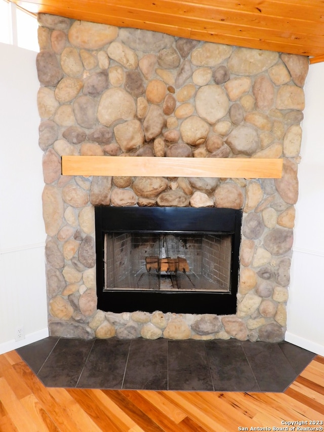 details featuring baseboards, wood finished floors, and a stone fireplace