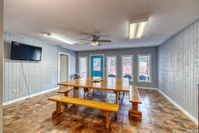 dining space featuring ceiling fan, a textured ceiling, and dark tile flooring