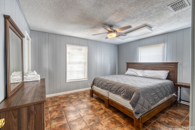 bedroom featuring dark tile flooring, a textured ceiling, multiple windows, and ceiling fan