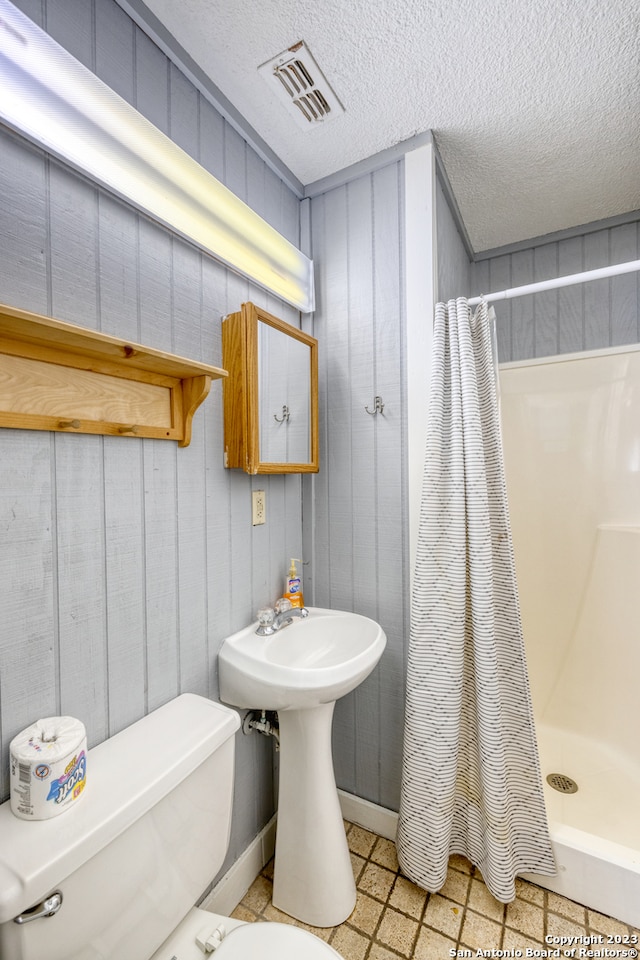 bathroom featuring a textured ceiling, a shower with curtain, tile flooring, and toilet