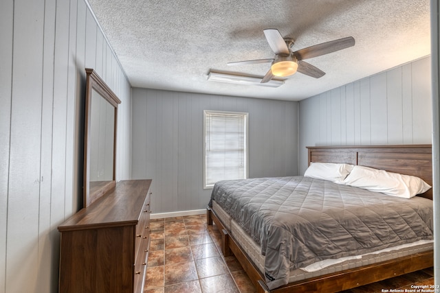 bedroom with dark tile flooring, a textured ceiling, and ceiling fan