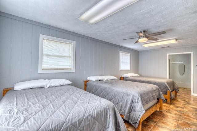 bedroom with light tile floors, ceiling fan, multiple windows, and a textured ceiling