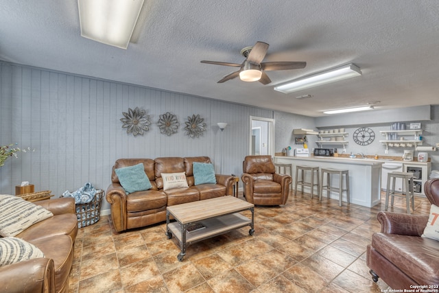 tiled living room with ceiling fan and a textured ceiling