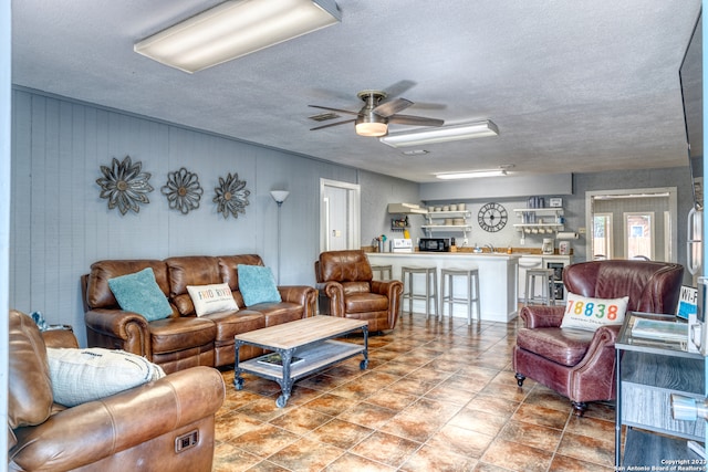 living room featuring light tile floors, a textured ceiling, and ceiling fan