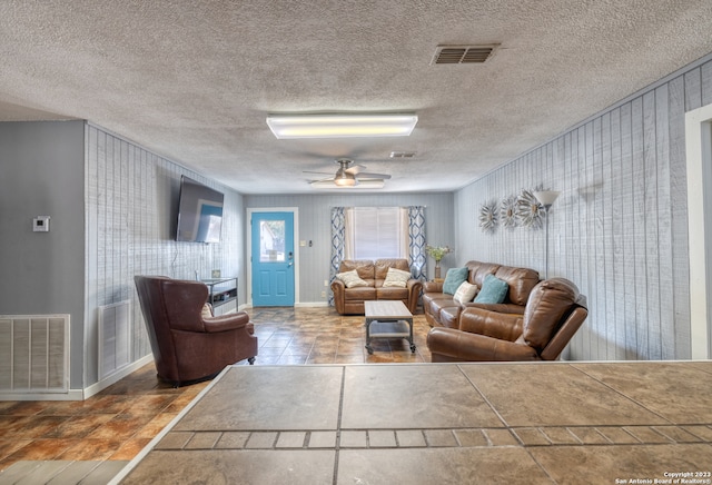 tiled living room with a textured ceiling and ceiling fan