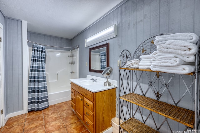 bathroom featuring wood walls, a textured ceiling, vanity with extensive cabinet space, tile flooring, and shower / tub combo