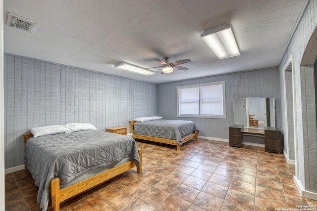 tiled bedroom with ceiling fan and a textured ceiling