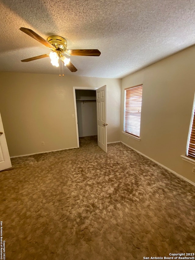 unfurnished bedroom featuring ceiling fan, a closet, dark colored carpet, and a textured ceiling