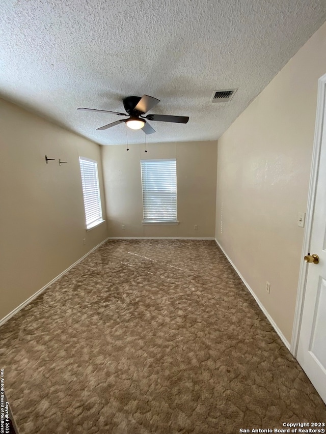 carpeted spare room with ceiling fan and a textured ceiling