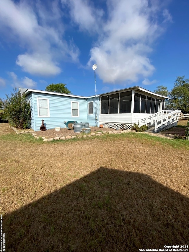 rear view of property featuring a lawn and a sunroom