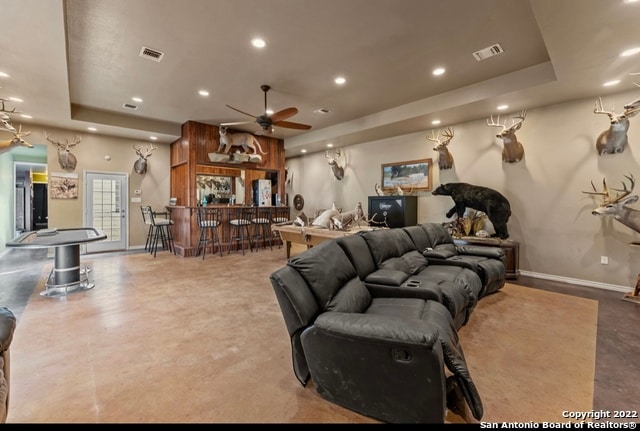 living room featuring a tray ceiling and ceiling fan