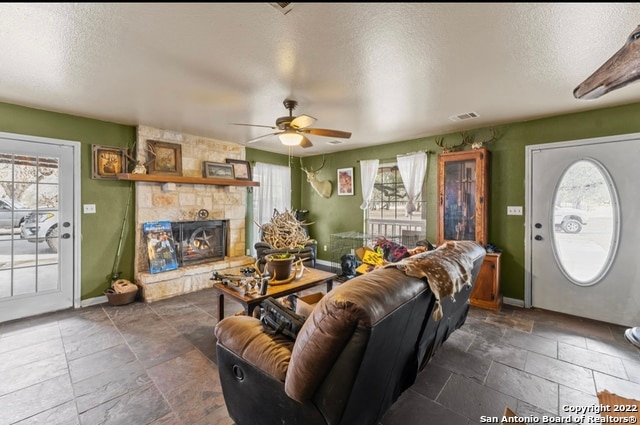 tiled living room with plenty of natural light, a fireplace, and ceiling fan