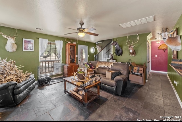 living room featuring ceiling fan and dark tile flooring