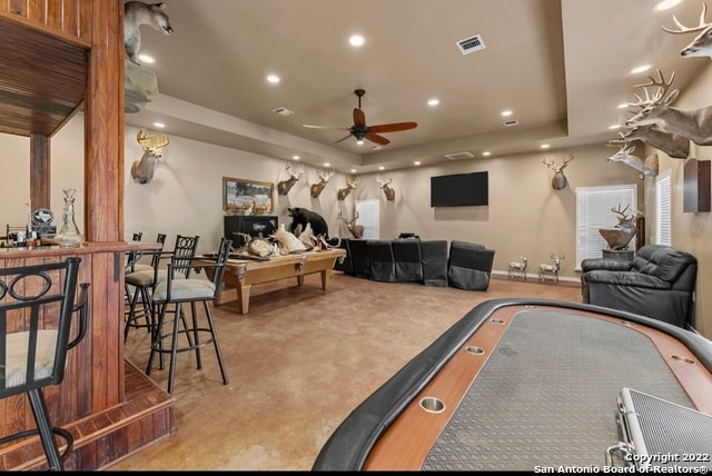 carpeted living room with a tray ceiling and ceiling fan