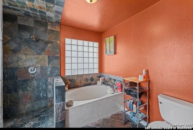 bathroom with plus walk in shower, tile flooring, and toilet