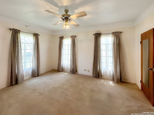 carpeted empty room featuring ceiling fan and crown molding