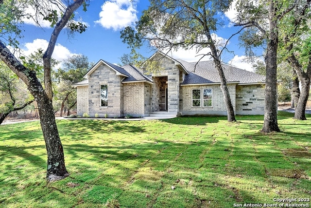 view of front of house with stone siding, brick siding, and a front yard