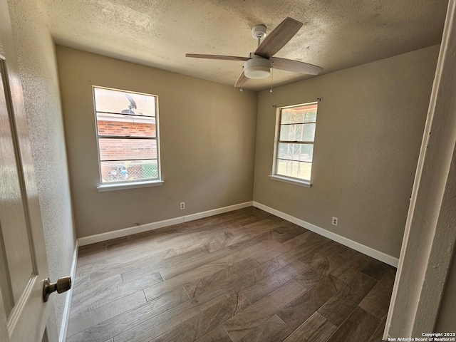 spare room with dark wood-type flooring, ceiling fan, and a textured ceiling