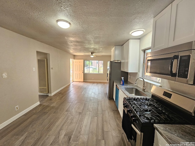 kitchen with ceiling fan, wood-type flooring, sink, stainless steel appliances, and white cabinets