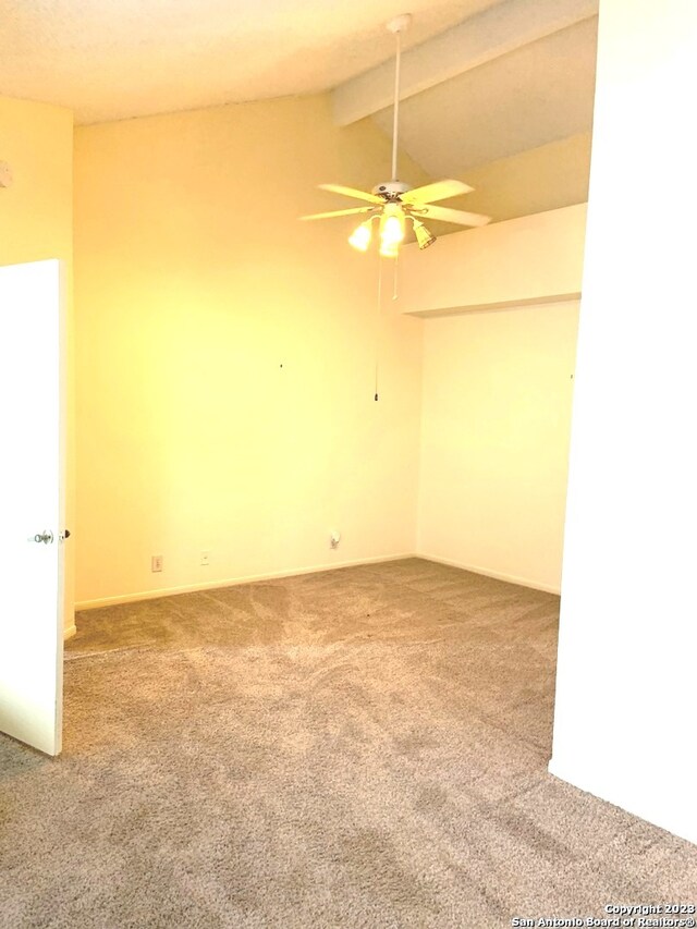 empty room featuring carpet, ceiling fan, and lofted ceiling with beams
