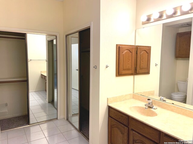 bathroom featuring toilet, vanity with extensive cabinet space, and tile flooring
