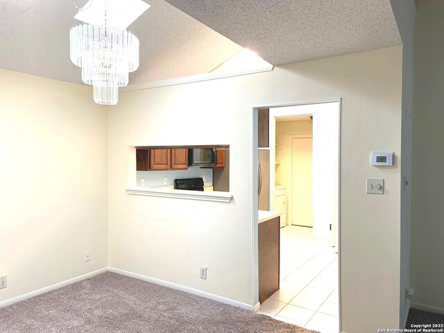 empty room featuring a textured ceiling, a chandelier, and light colored carpet