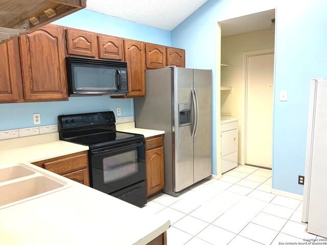 kitchen featuring light tile floors, washer / clothes dryer, and black appliances