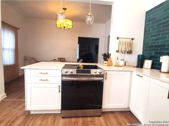 kitchen featuring decorative light fixtures, light hardwood / wood-style floors, white cabinets, stainless steel range with electric cooktop, and kitchen peninsula