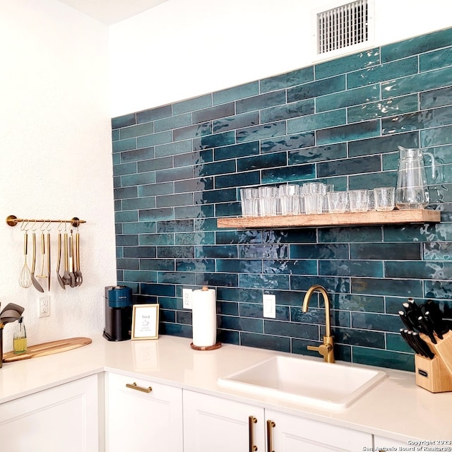 interior space featuring white cabinets, sink, and tasteful backsplash