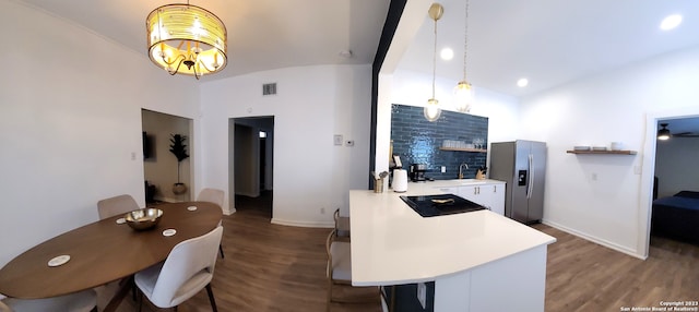 kitchen featuring hardwood / wood-style floors, decorative light fixtures, a kitchen breakfast bar, and stainless steel refrigerator with ice dispenser