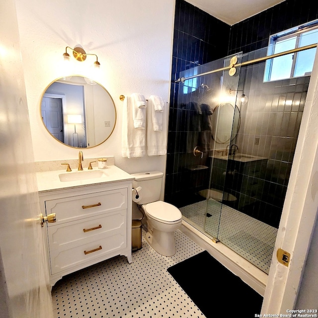 bathroom featuring toilet, tile floors, vanity, and a shower with shower door