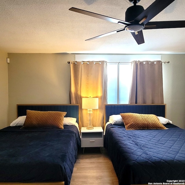 bedroom featuring ceiling fan, a textured ceiling, and wood-type flooring
