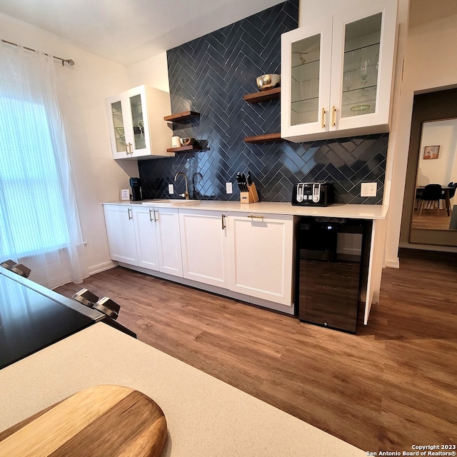 bar with sink, white cabinets, light hardwood / wood-style flooring, backsplash, and wine cooler