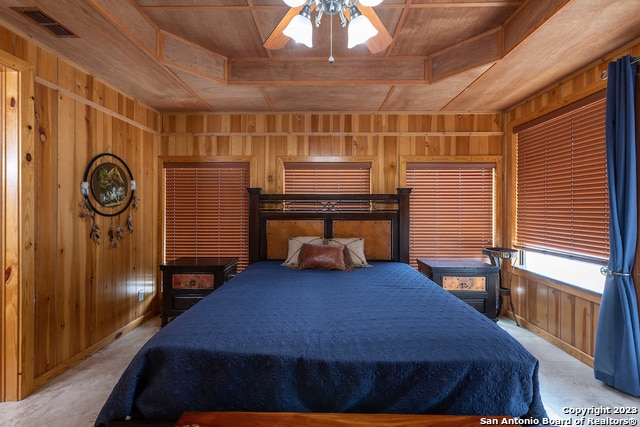 bedroom with ceiling fan, wood walls, carpet flooring, and wooden ceiling