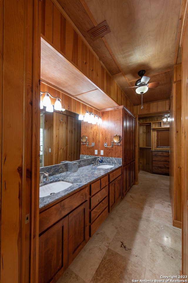 bathroom featuring wooden walls, vanity, and ceiling fan