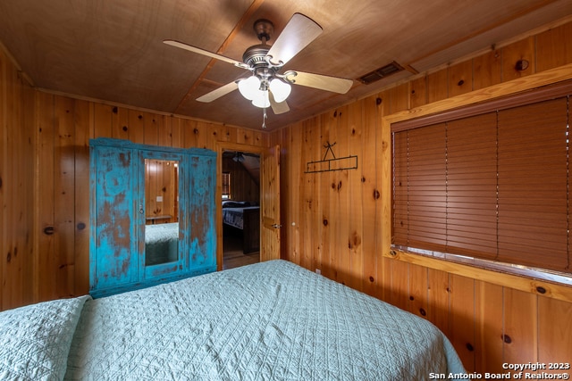 bedroom featuring wood ceiling, wooden walls, ceiling fan, and a closet