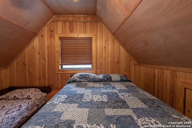 bedroom with wooden walls and vaulted ceiling