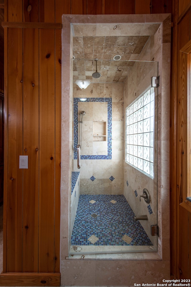 bathroom with wood walls and a shower with door