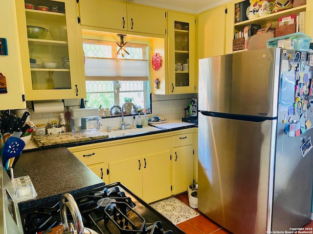 kitchen with backsplash, crown molding, stainless steel refrigerator, and light tile floors