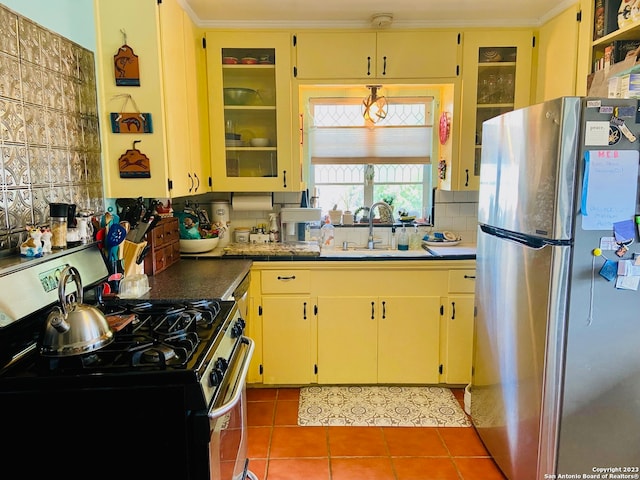 kitchen with appliances with stainless steel finishes, tile flooring, backsplash, sink, and ornamental molding