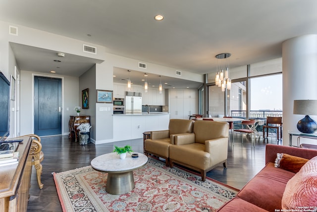 living room with a notable chandelier, sink, and dark wood-type flooring