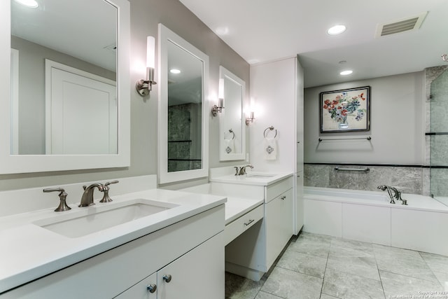 bathroom with a relaxing tiled bath, vanity, and tile flooring