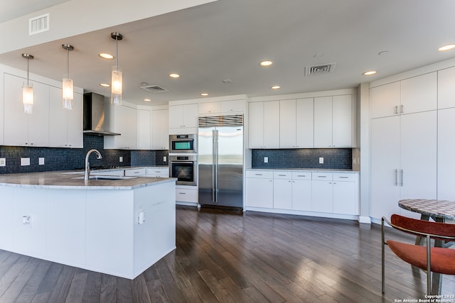 kitchen featuring white cabinetry, wall chimney range hood, and appliances with stainless steel finishes