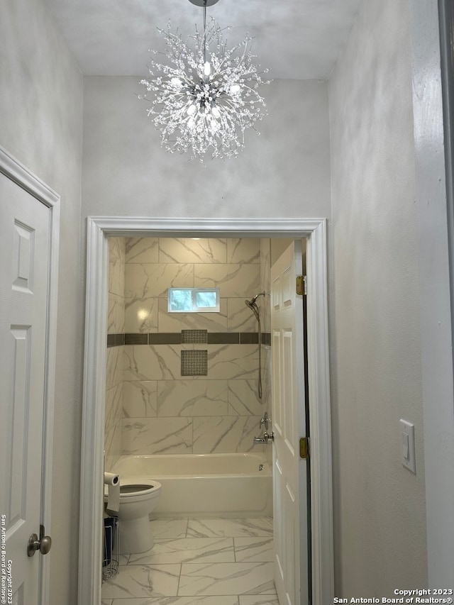 bathroom featuring tiled shower / bath combo, a notable chandelier, tile floors, and toilet