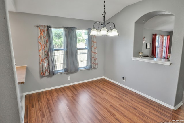 unfurnished dining area with a notable chandelier, wood-type flooring, and lofted ceiling