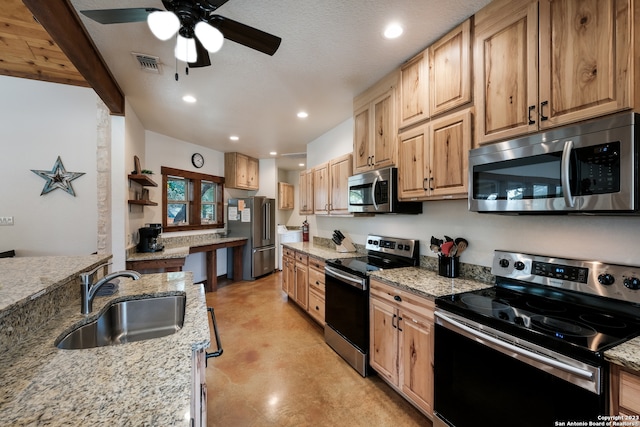 kitchen with ceiling fan, appliances with stainless steel finishes, sink, a textured ceiling, and light stone counters