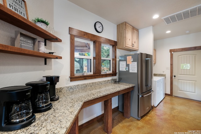 kitchen with light brown cabinets, light stone counters, and stainless steel refrigerator