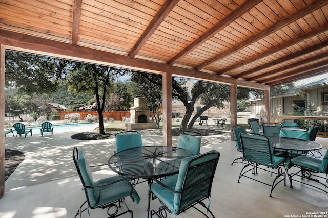 view of patio / terrace with an outdoor stone fireplace and a fenced in pool