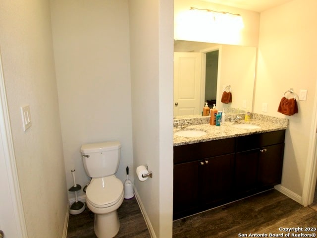 bathroom featuring oversized vanity, hardwood / wood-style floors, toilet, and double sink