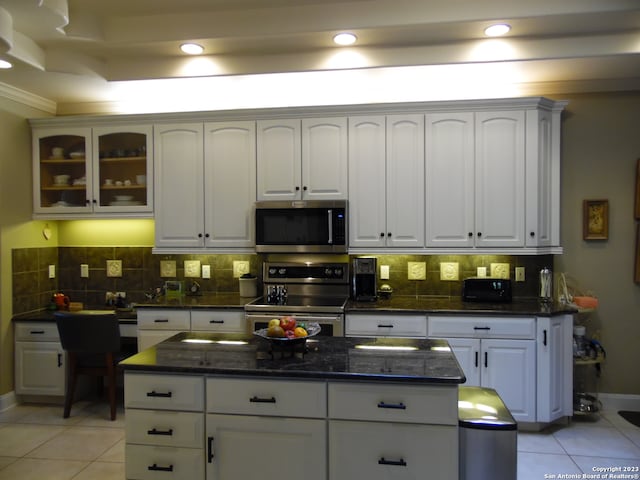 kitchen with stainless steel appliances, tasteful backsplash, light tile floors, and white cabinets